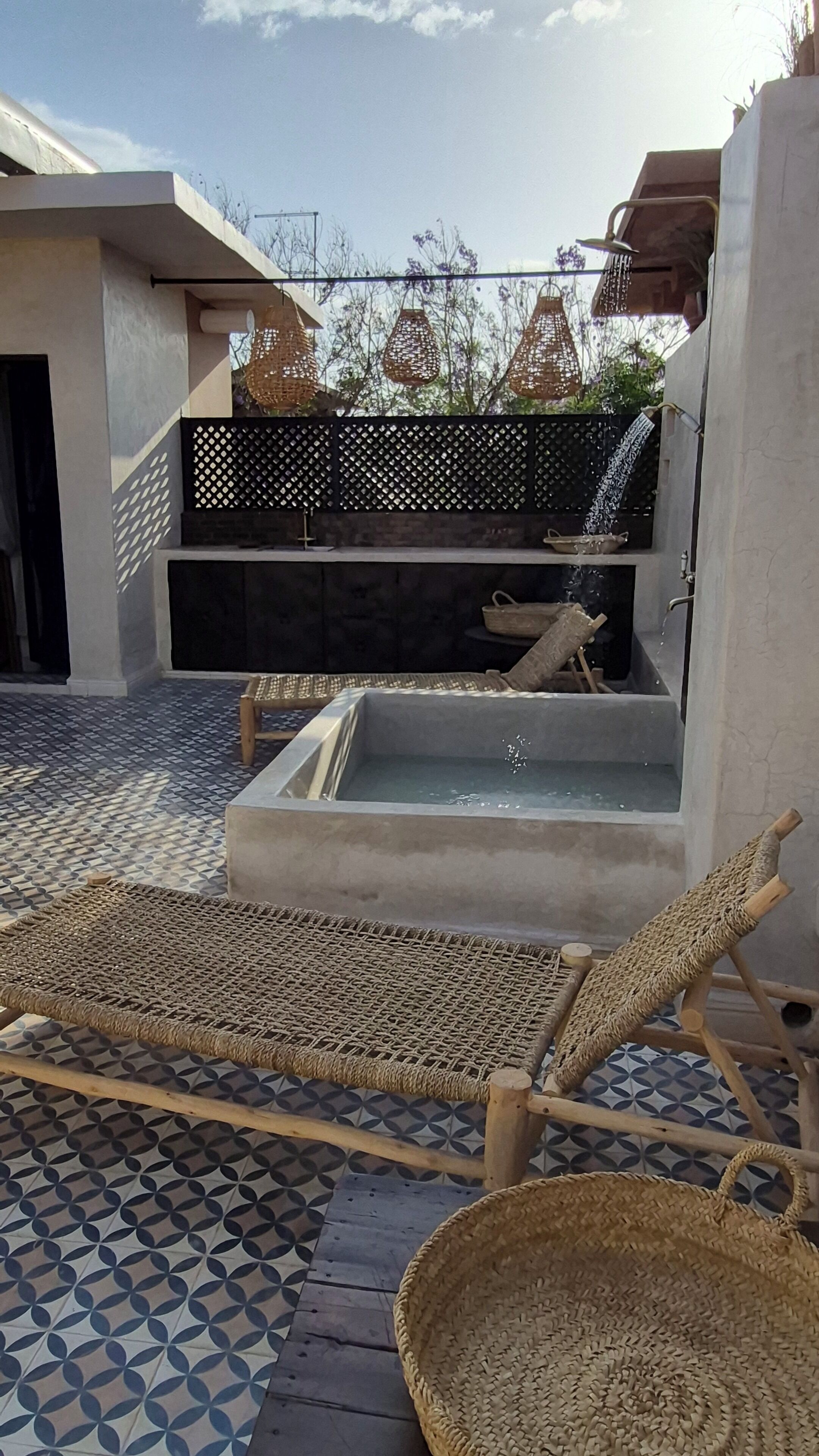 Une terrasse sur le toit avec un évier en béton, des chaises longues et un panier en osier.