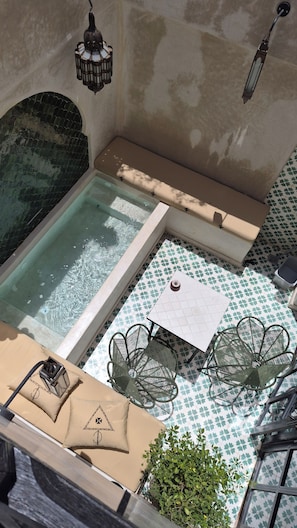 Un espace piscine aménagé sur le toit, comprenant un jacuzzi, des sièges et une table avec des chaises.