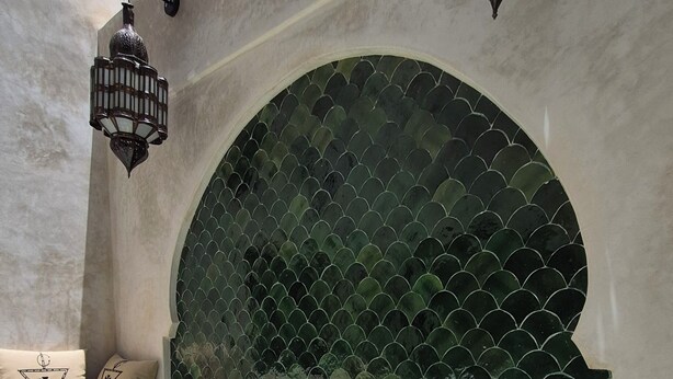 Un'area benessere con piscina, zona relax con cuscini e una parete ad arco decorativa.