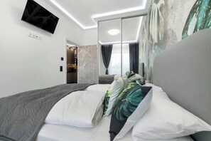 Ein modernes Hotelzimmer mit einem Bett, einem Flachbildfernseher, einem Spiegel und Blick auf die Stadt durch das Fenster.