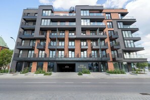 Ein mehrgeschossiges Gebäude mit modernem architektonischen Design, mit Balkonen, großen Fenstern und einem markanten Eingang.