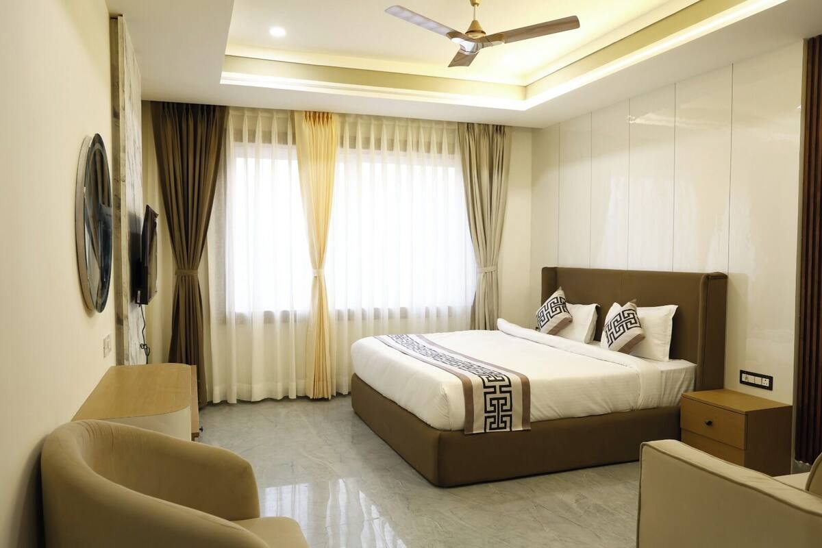 Una habitación de hotel con cama, escritorio, silla, ventilador de techo y televisión.