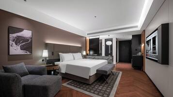 Una habitación de hotel moderna con una cama grande, un sofá, un escritorio y un televisor.