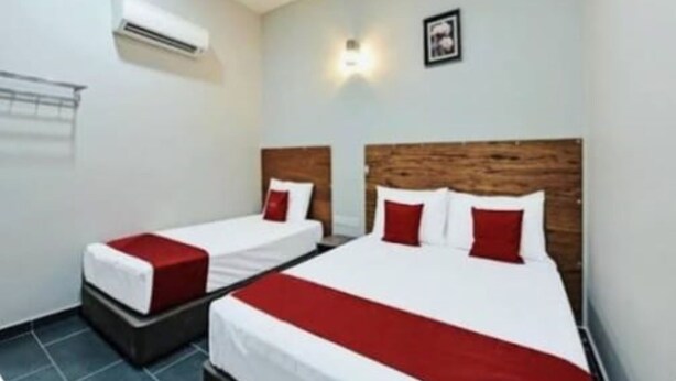 A hotel room with two beds, a wooden headboard, a red accent pillow, and an air conditioning unit. - RS Hotel (Johor Bahru)