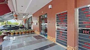 A hotel entrance with a tiled walkway, potted plants, and a covered area. - RS Hotel (Johor Bahru)