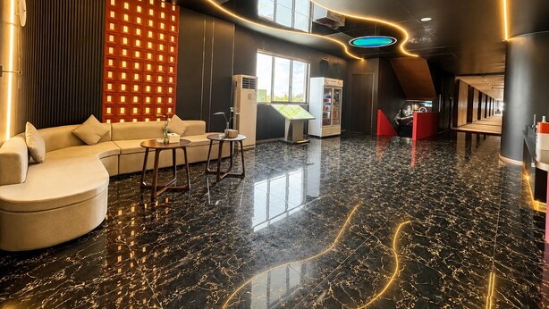 Un lobby moderno con piso de mármol, un sofá, mesas y una lámpara colgante grande.