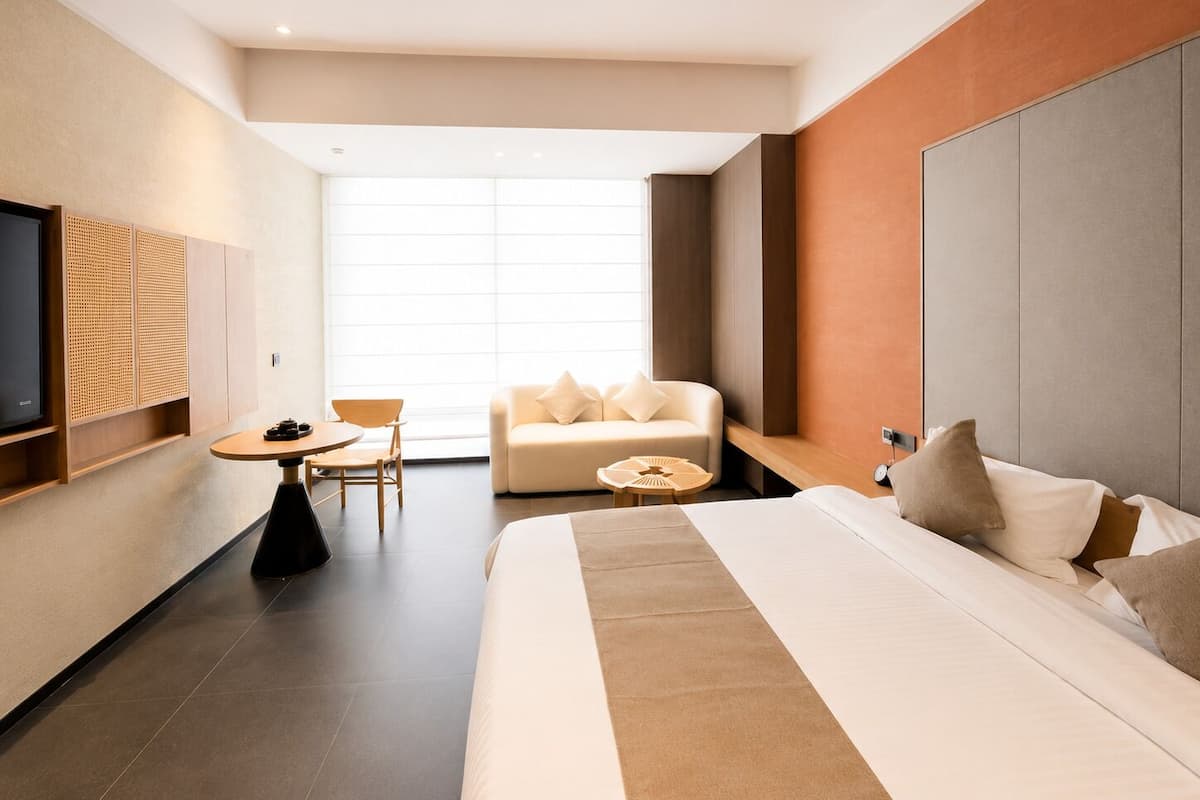 Una habitación de hotel moderna con una cama, un sofá, un televisor y una pequeña mesa.