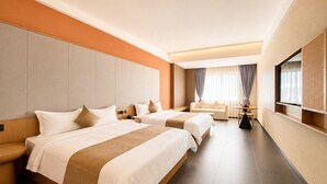 Habitación de hotel con dos camas, un sofá, una mesita y un televisor.