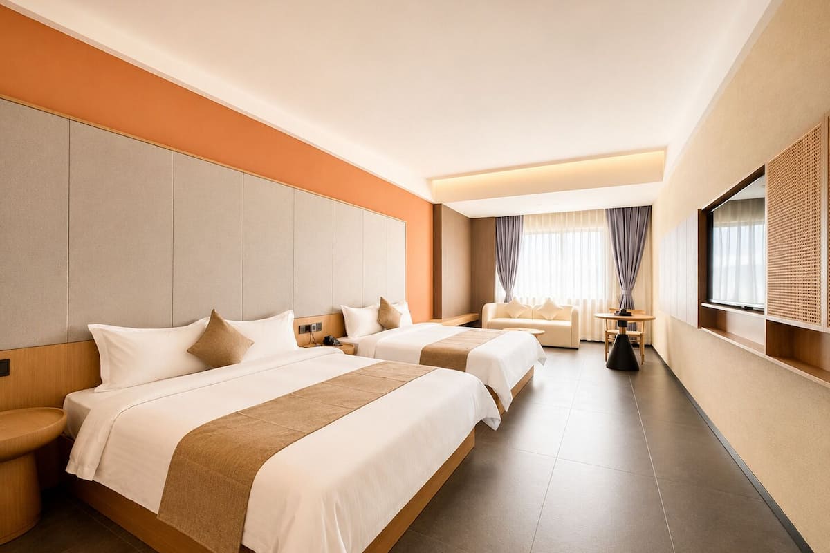 Habitación de hotel con dos camas, un sofá, una mesita y un televisor.