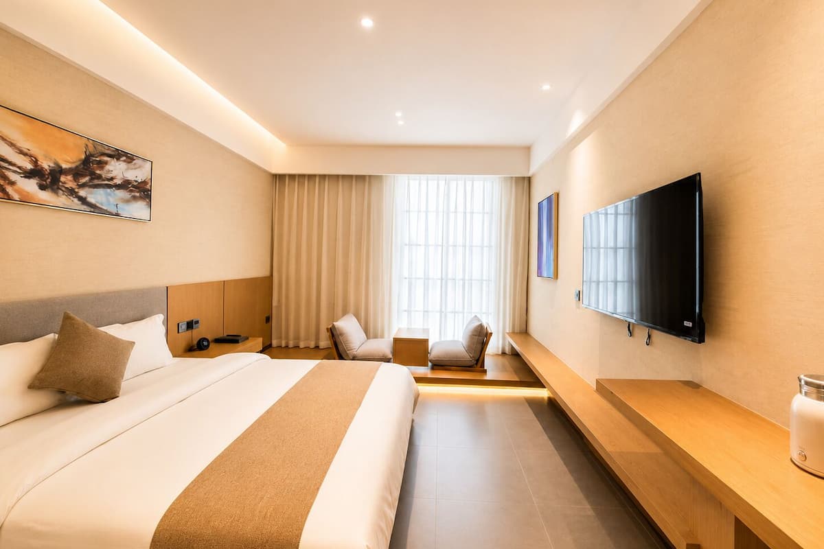 Una habitación de hotel con una cama grande, televisión, escritorio y una silla.