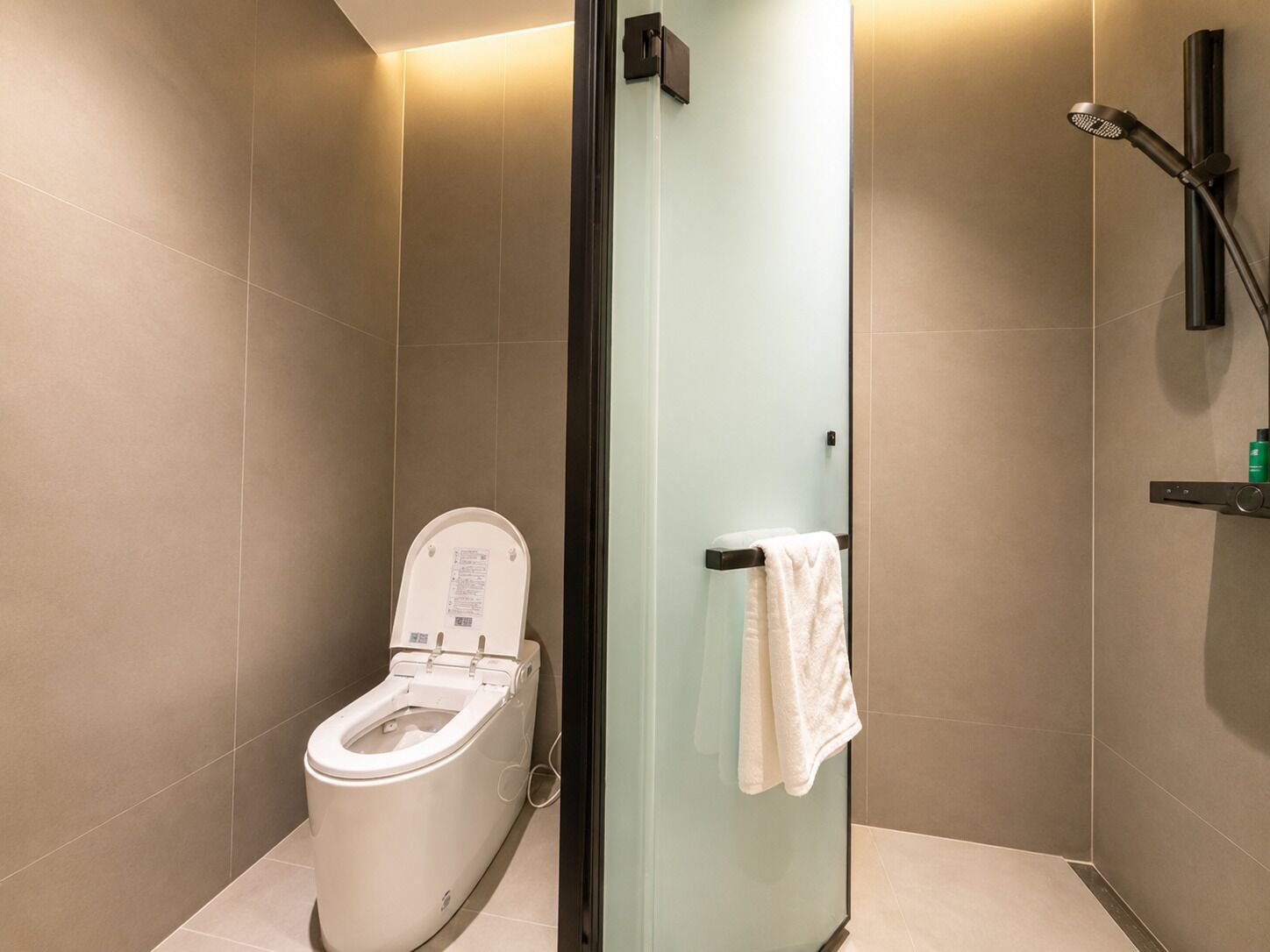 Une salle de bain moderne équipée de toilettes, d’une douche à parois de verre et d’un porte-serviettes.