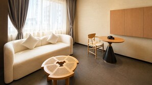 Una habitación de hotel moderna con un sofá, una mesa redonda de madera y una silla.