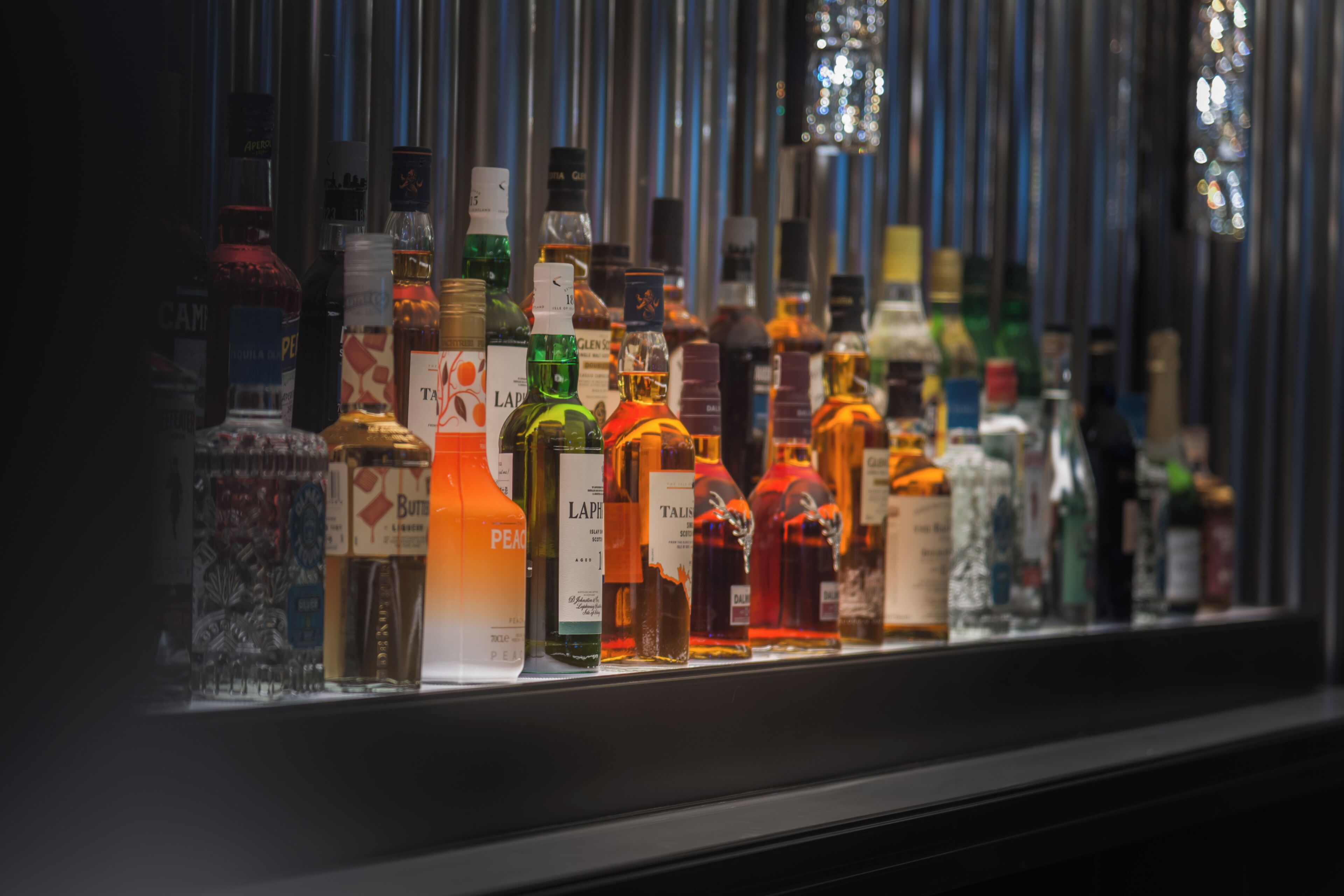 A variety of liquor bottles displayed in a refrigerated case.