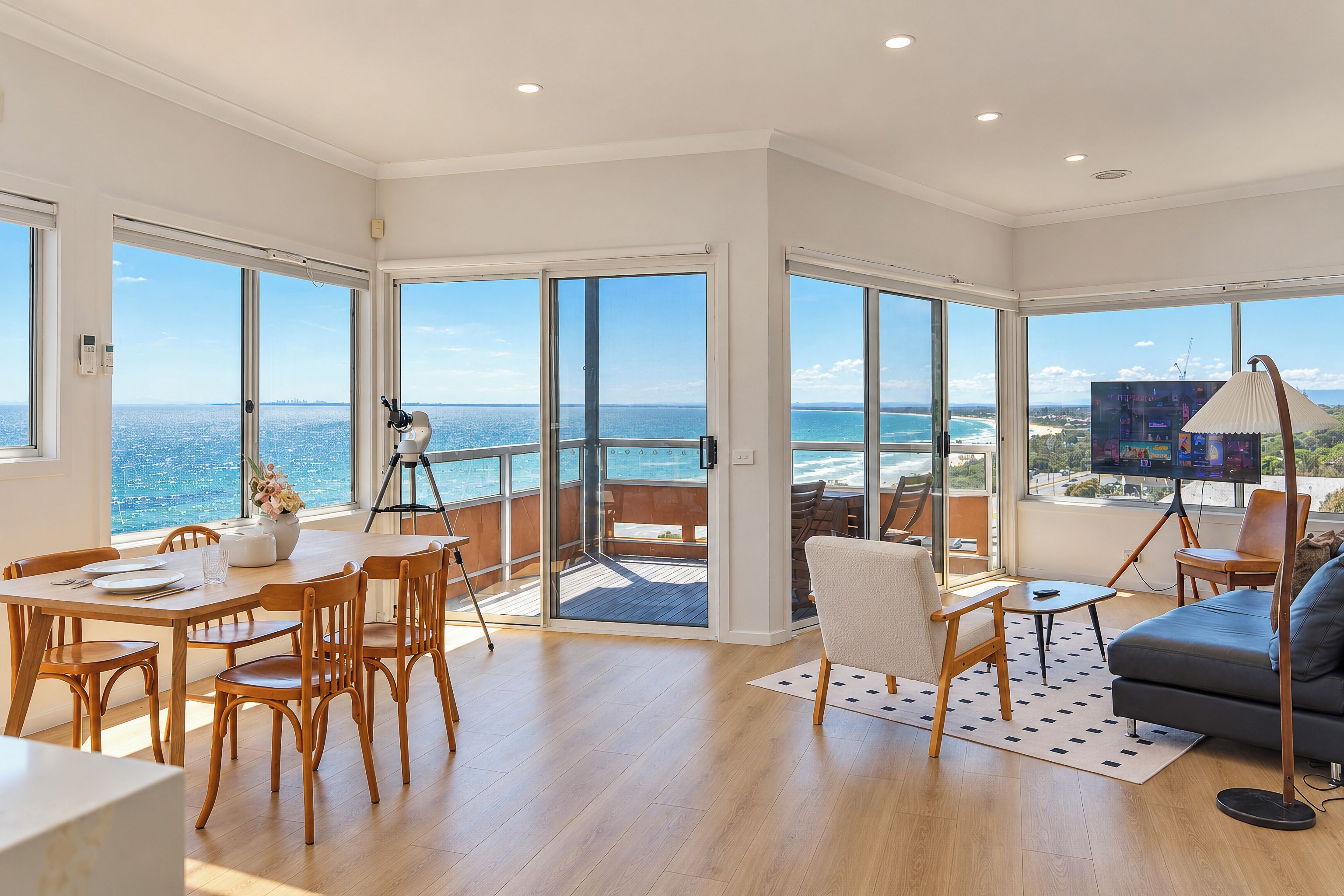 A spacious living area with a large sliding glass door leading to a balcony with a view of the sea.