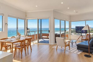 A spacious living area with a large sliding glass door leading to a balcony with a view of the sea. - Pudding's Home: Exclusive Oceanfront Experience (Frankston)