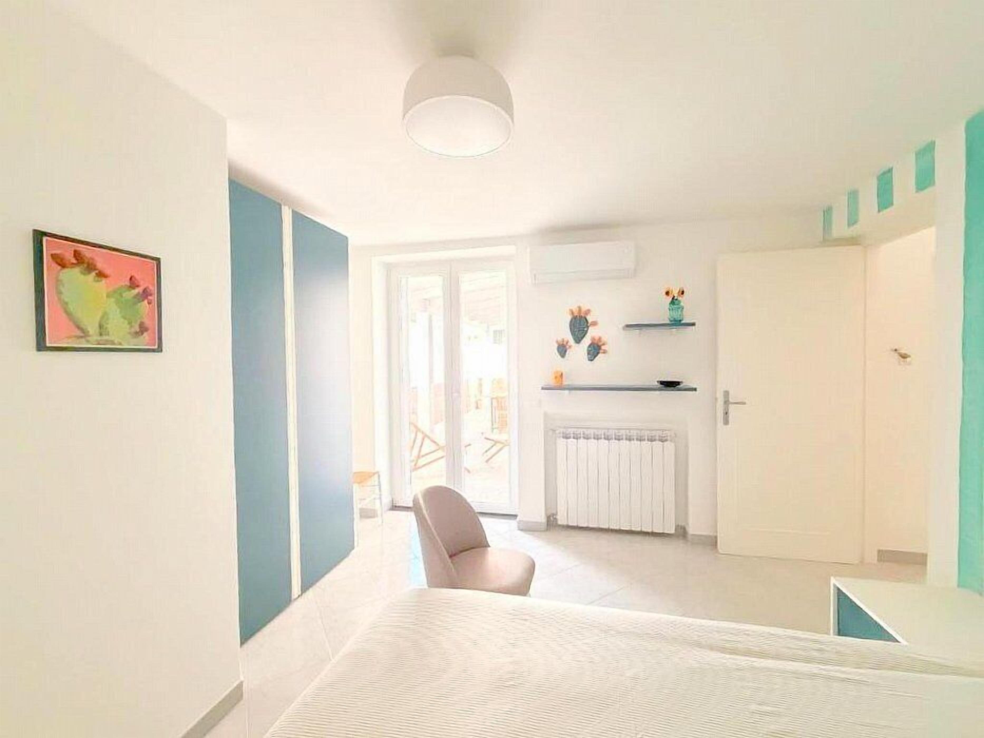 Une chambre d’hôtel moderne équipée d’un lit, d’une chaise, d’un radiateur et d’une porte donnant sur un balcon.