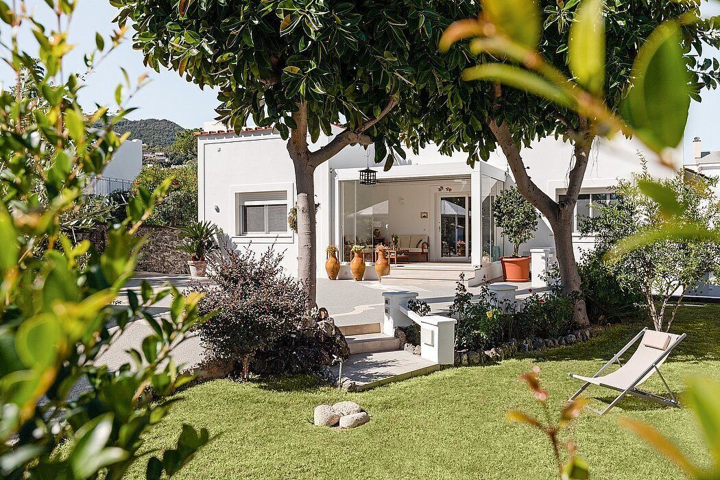 A modern house with a patio, a lawn, and a lounge chair.
