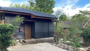 A wooden house with a tiled roof, a front door, and a small porch area.
