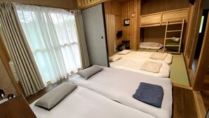 A compact RV bedroom with two beds, a small seating area, and a wooden bunk bed.