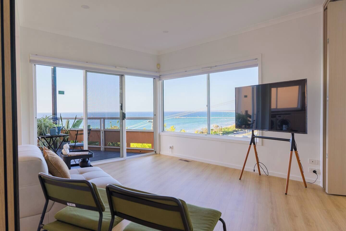 A spacious room with a large sliding glass door leading to a balcony with a view of the sea.
