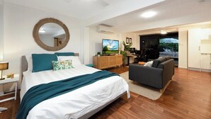 Habitació d'hotel moderna amb un llit gran, un sofà, una televisió i un balcó amb vistes.