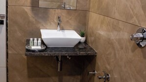 Un baño con lavamanos blanco, espejo, toallero y retrete.