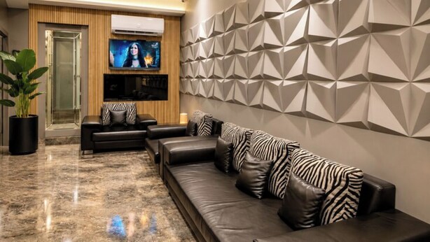 Una sala de estar moderna con un sofá, un televisor y un diseño geométrico en la pared.