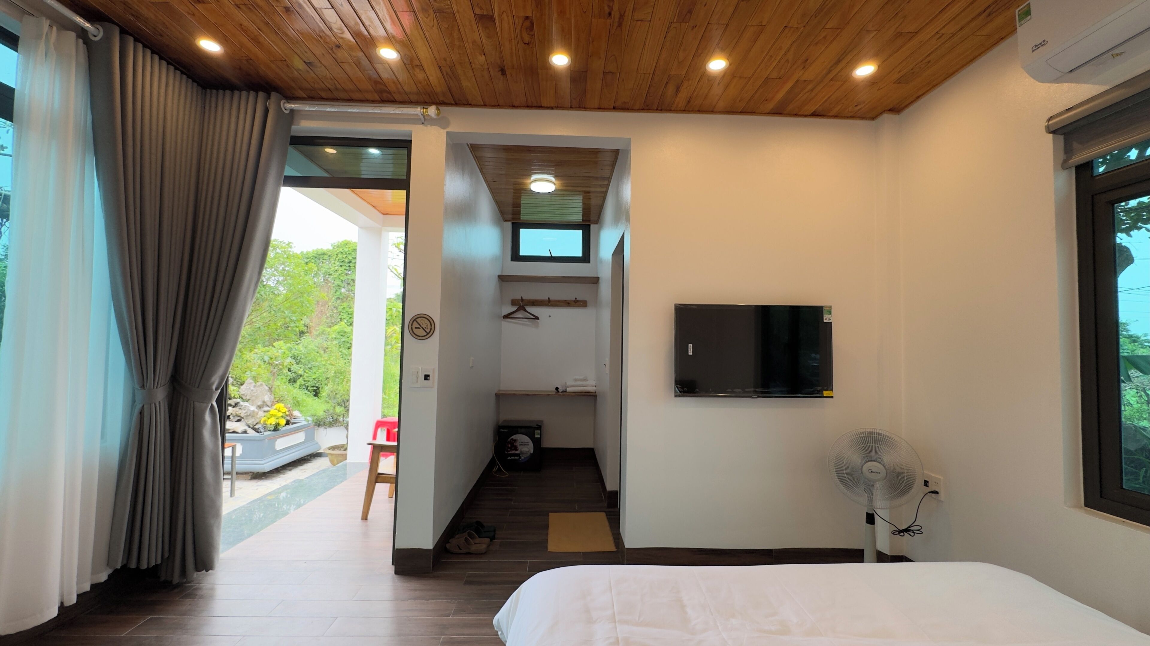 Un dormitorio con cama, televisión, ventilador y vistas al exterior.