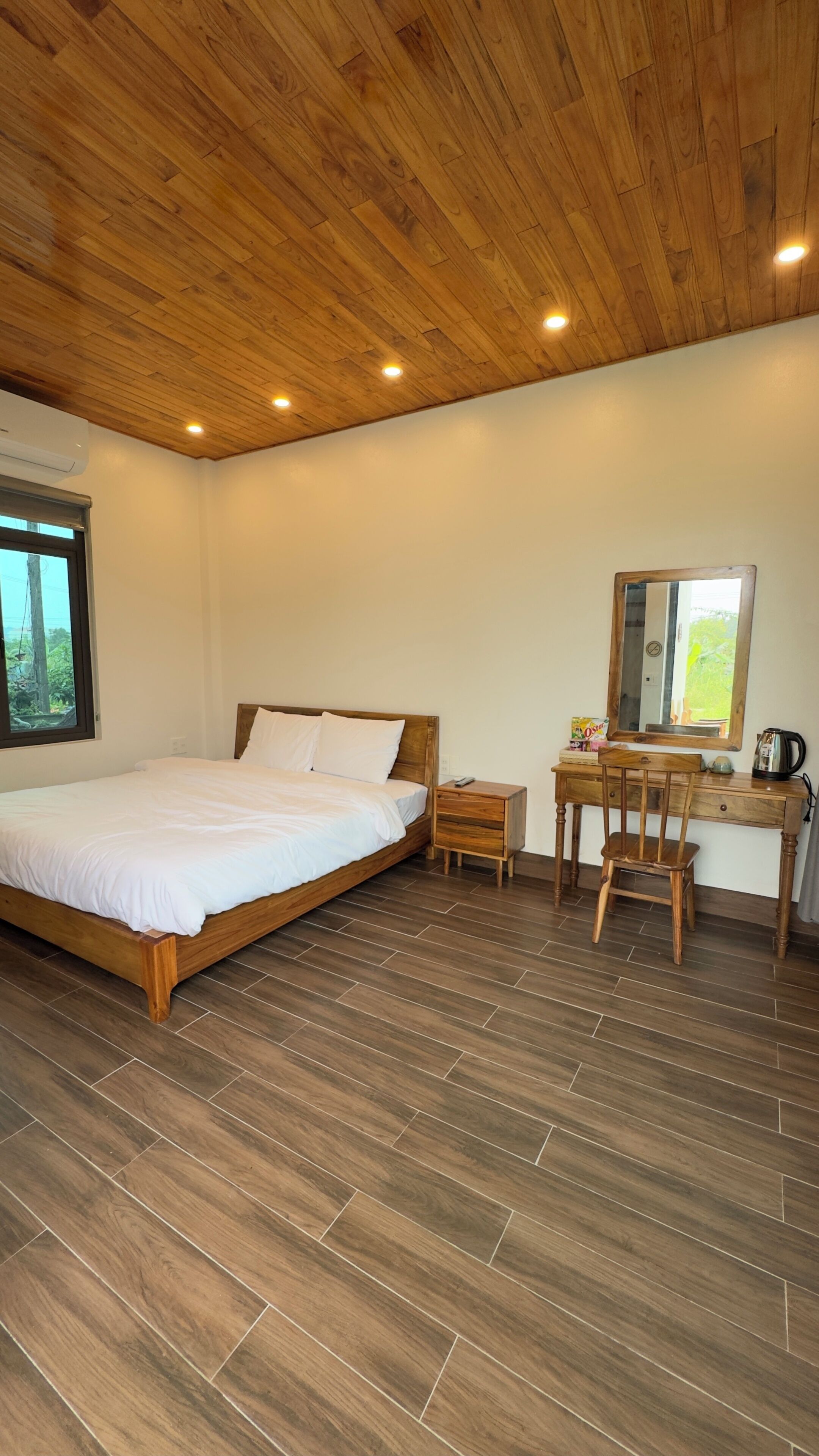 Une chambre avec un plafond en bois, un lit, un bureau avec une chaise et une fenêtre.