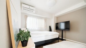 A modern bedroom with a bed, a TV, an air conditioner, and a potted plant. - Sunlit Canopy (Shinjuku)