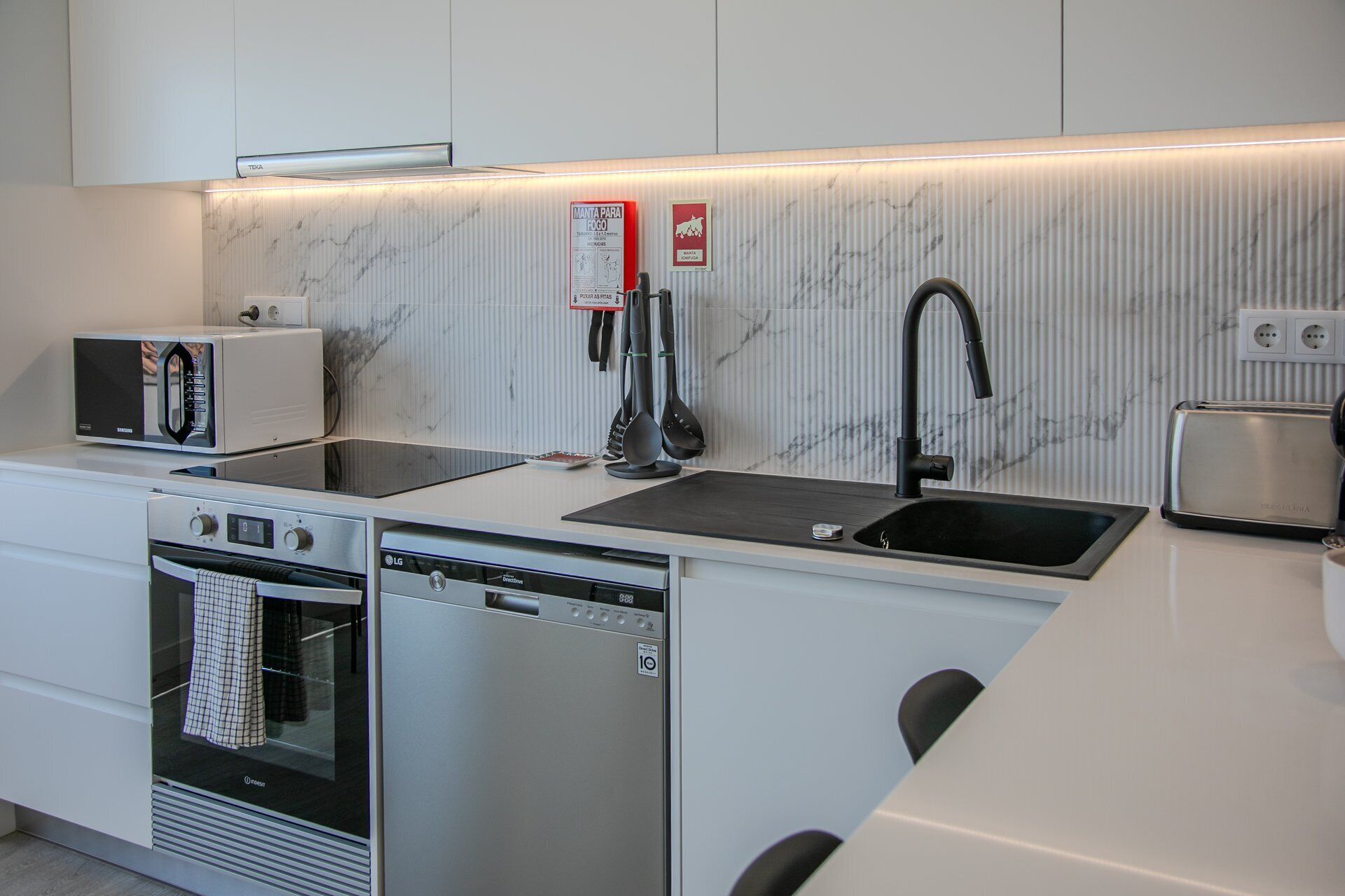 Een moderne keuken met een magnetron, broodrooster, spoelbak en vaatwasser.