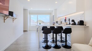 Une cuisine moderne avec un coin bar, des tabourets de bar et une vue sur l’extérieur.