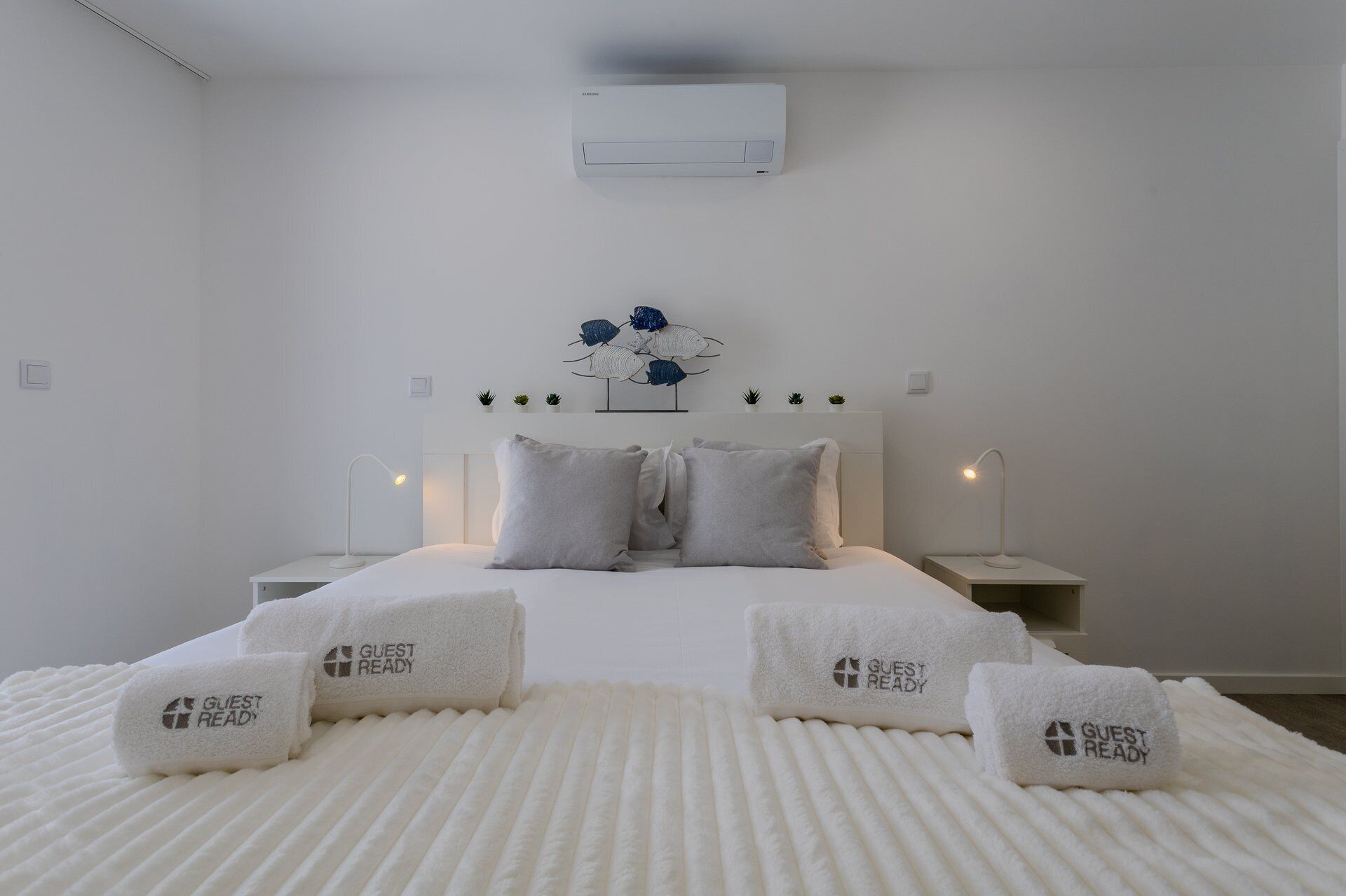 Une chambre d’hôtel moderne équipée d’un lit, de lampes de chevet, d’un climatiseur mural et d’un élément décoratif fixé au mur.