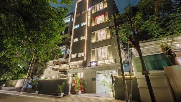 A multi-story hotel with a modern facade, illuminated signage, and outdoor plants.