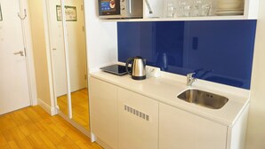 Cozinha compacta com forno embutido, chaleira, pia e micro-ondas.