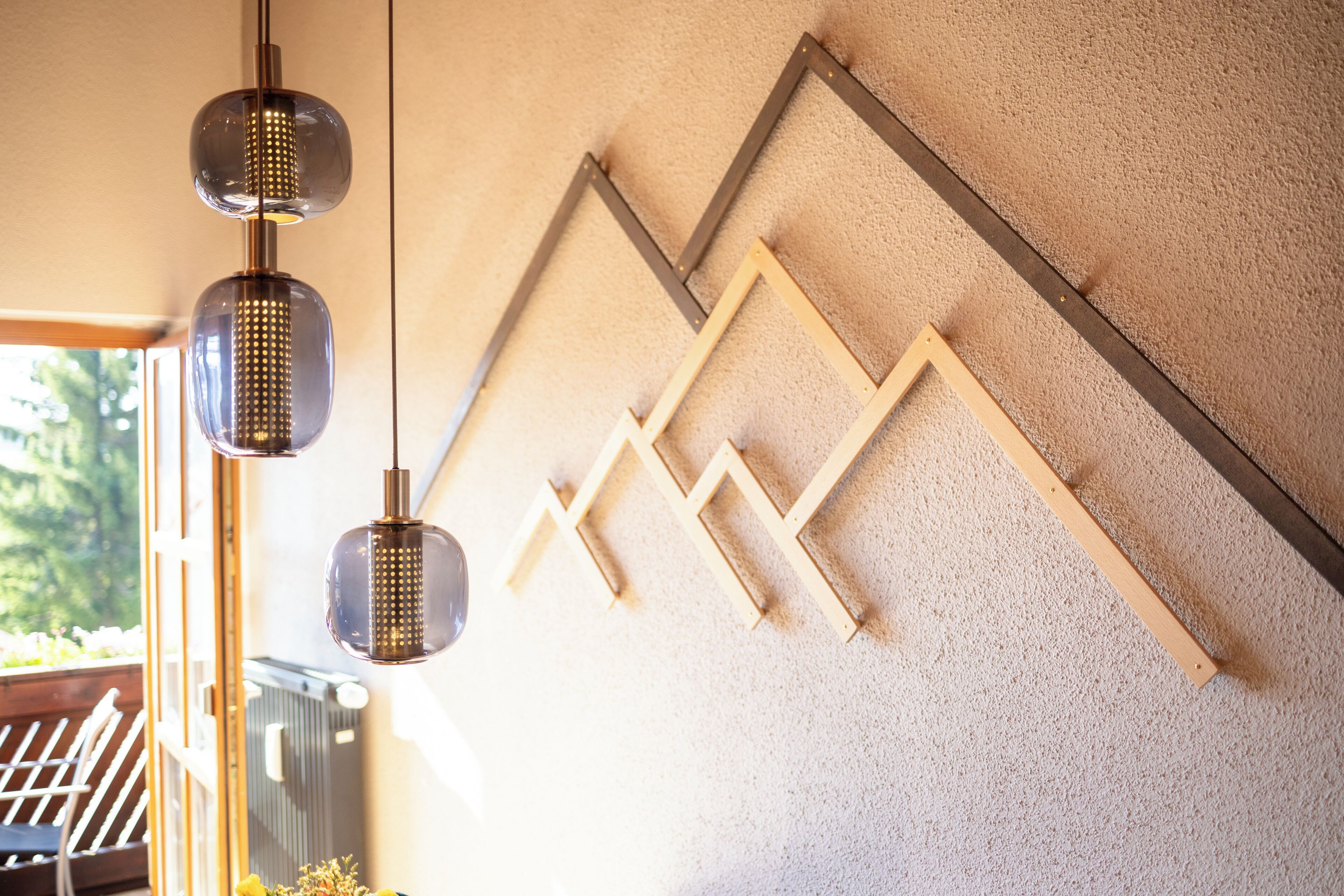Un parete con una struttura geometrica in legno e lampade pendenti.