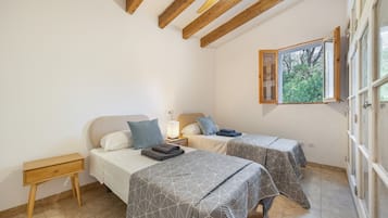 Un dormitorio con dos camas, techo de madera, ventana con vistas y una mesita de noche.