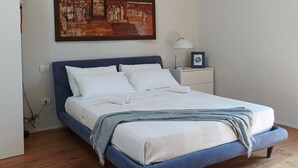 Ein Schlafzimmer mit Bett, Nachttisch, Lampe und einem Bild an der Wand.