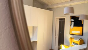 Ein modernes Interieur mit Holzboden, weißen Schränken und einem gelben Akzentstuhl.