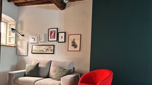 Ein Wohnzimmer mit einem beigefarbenen Sofa, einem roten Sessel und gerahmten Bildern an der Wand.