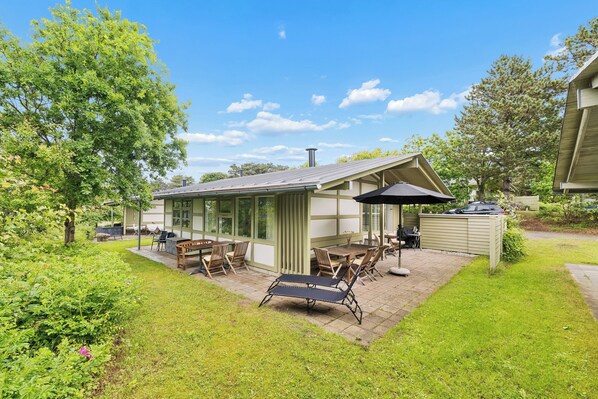 Et hus med en patio, udendørs møbler og en overdækket siddekrog.