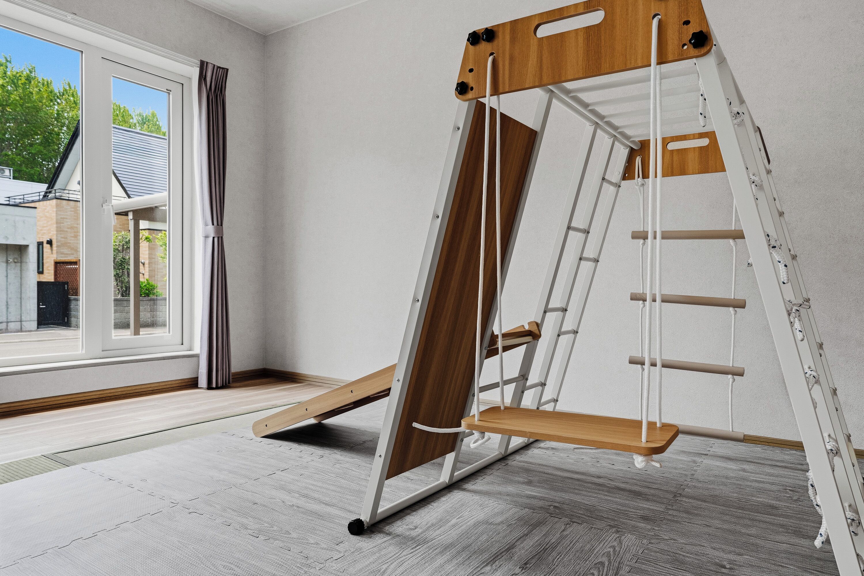 Une pièce avec une grande fenêtre, une échelle en bois et un mur blanc.