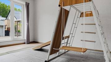 Une pièce avec une grande fenêtre, une échelle en bois et un mur blanc.