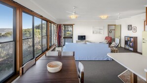 Une chambre à coucher avec un grand lit, un bureau, une chaise, une télévision et une bibliothèque.