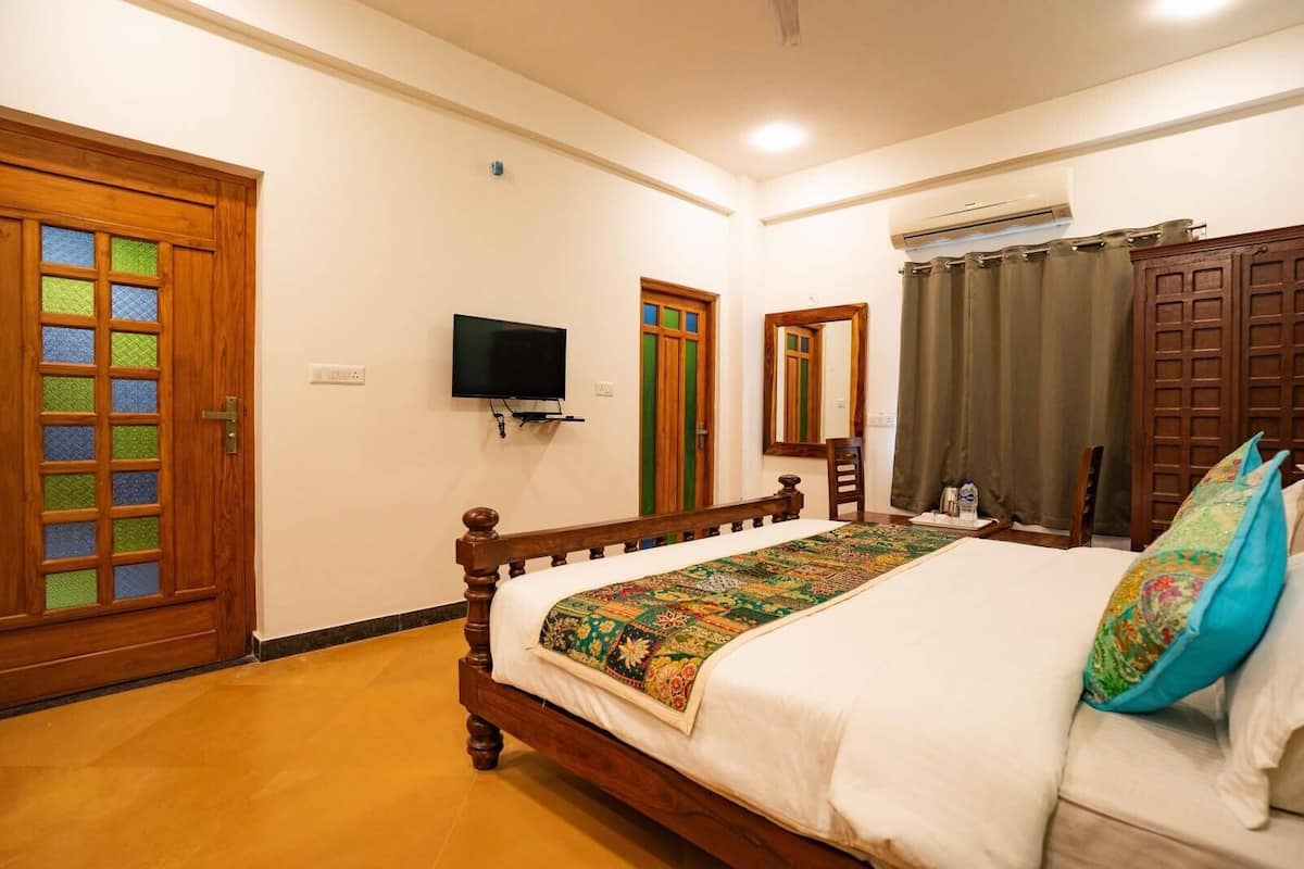 A bedroom with a wooden bed, a television on the wall, a mirror, and a door with a stained glass design.