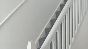 A staircase with white railings and a dark-colored handrail.