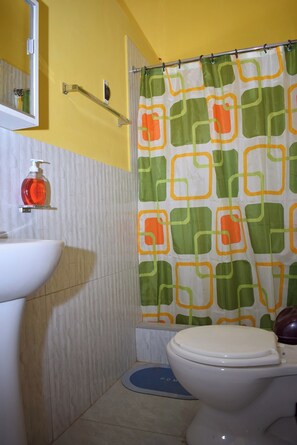 A bathroom with a toilet, a sink, and a shower curtain with a geometric pattern. - Vrbo Property (Huaraz)