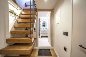 Una escalera de madera que termina en un felpudo negro, dando acceso a una puerta.