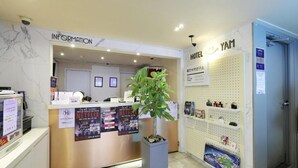 A reception desk with a plant, information signs, and a hotel sign.