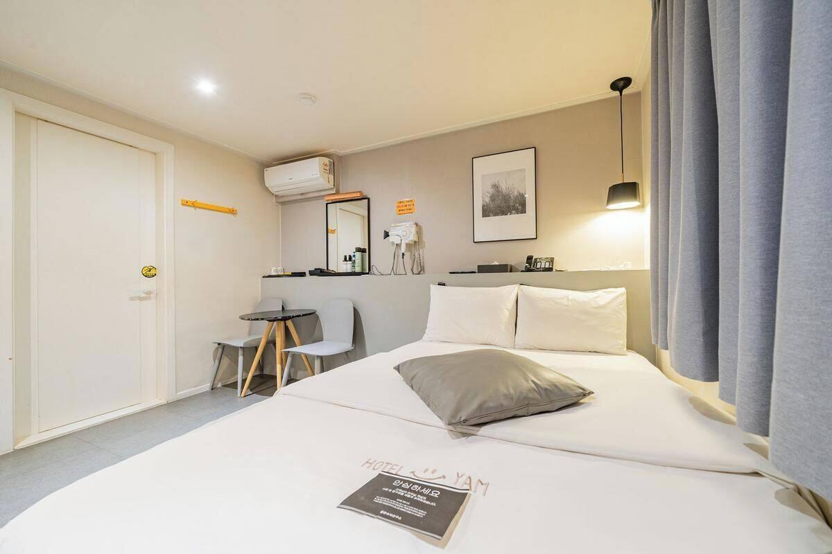A hotel room with a bed, a desk, a chair, a mirror, and a picture on the wall.